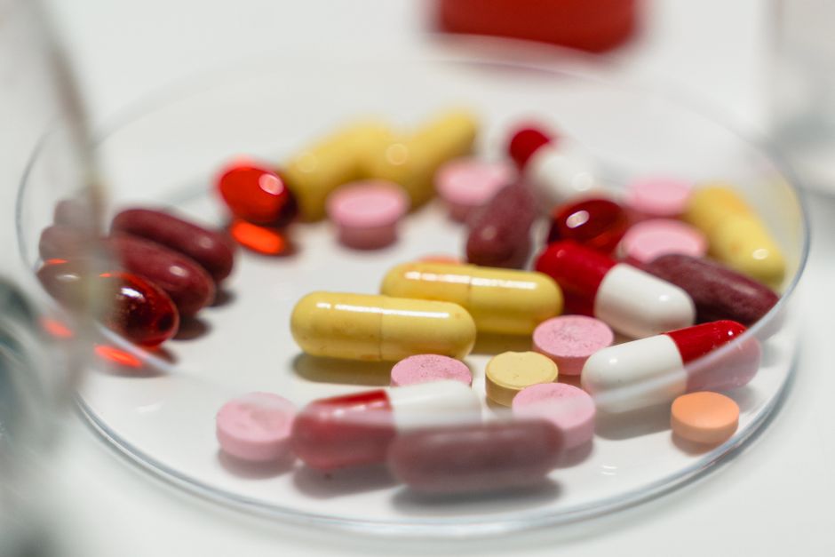Close-up of oxycodone tablets and capsules next to a prescription bottle on a pharmacy counter