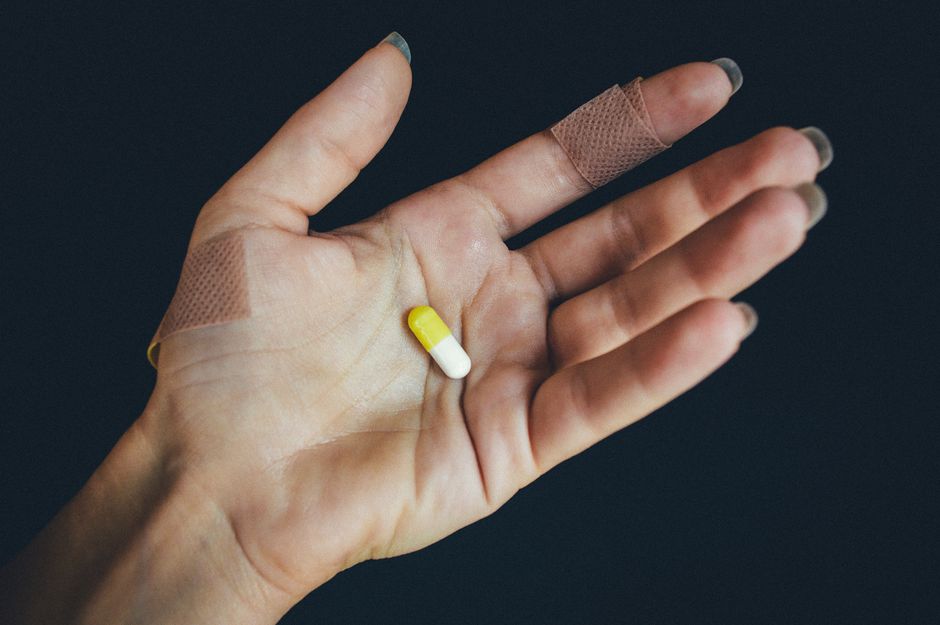 Patient holding an oxycodone pill bottle while managing a sudden breakthrough pain flare