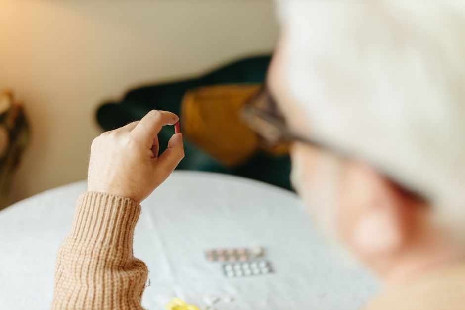 Person holding a pill and glass of water while checking the time for Adderall onset