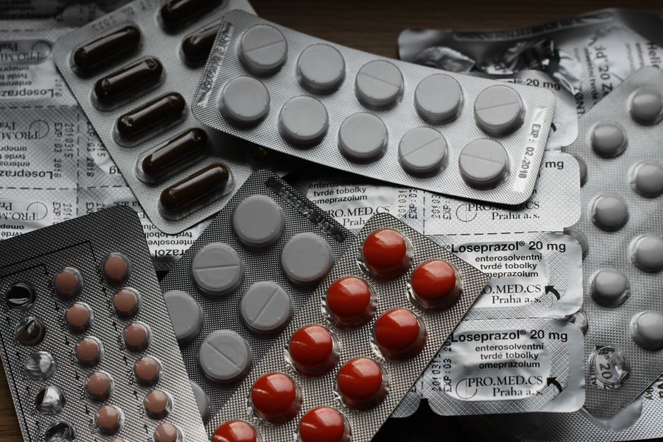 Person holding stomach in discomfort next to oxycodone pill bottle, representing opioid-induced constipation