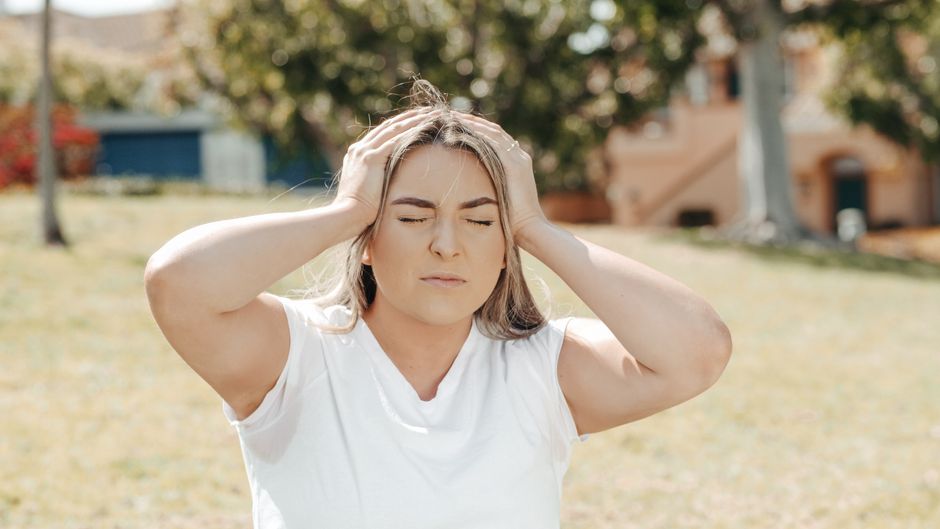 Person holding their head due to a headache, a possible side effect of oxycodone