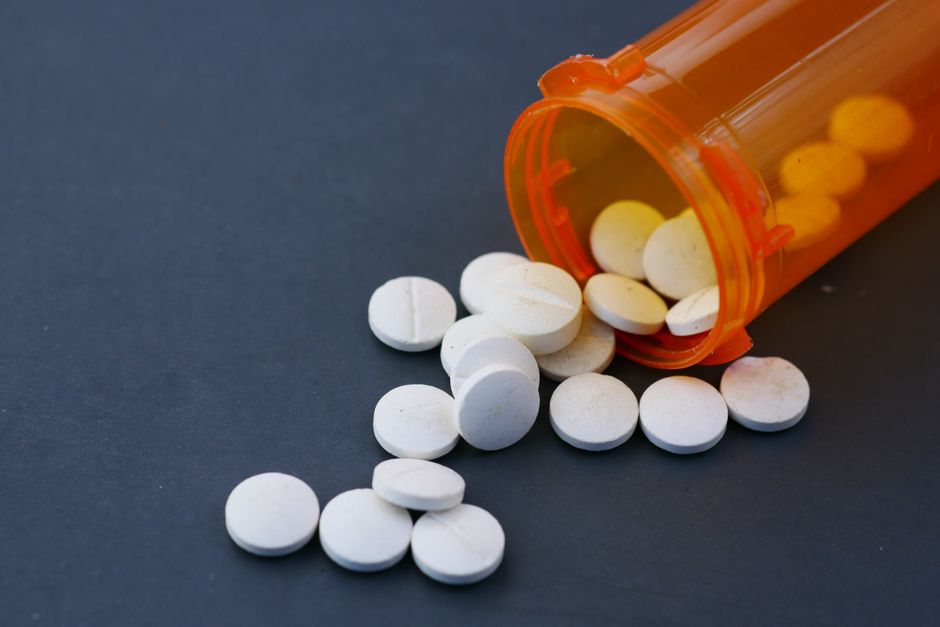 Person looking concerned while holding a prescription bottle of oxycodone pills