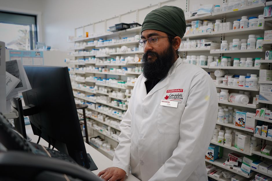 Pharmacist reviewing an oxycodone prescription bottle at the pharmacy counter