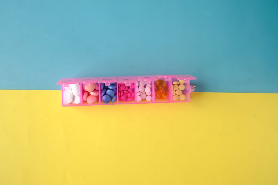 Pill organizer next to a clock representing the best time to take oxycodone for consistent pain control