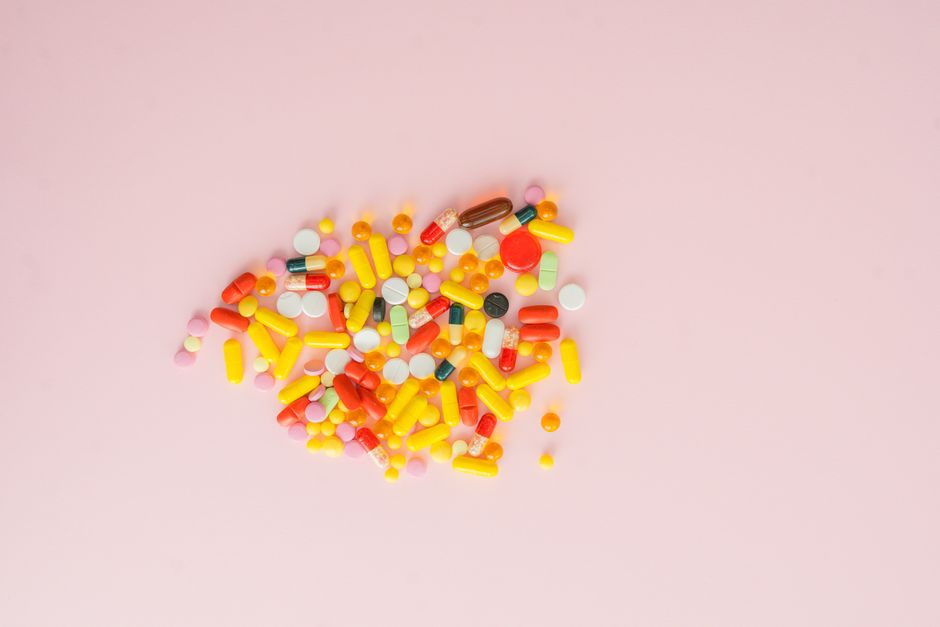 Vitamin supplements and pills next to a prescription bottle representing oxycodone and vitamin safety considerations