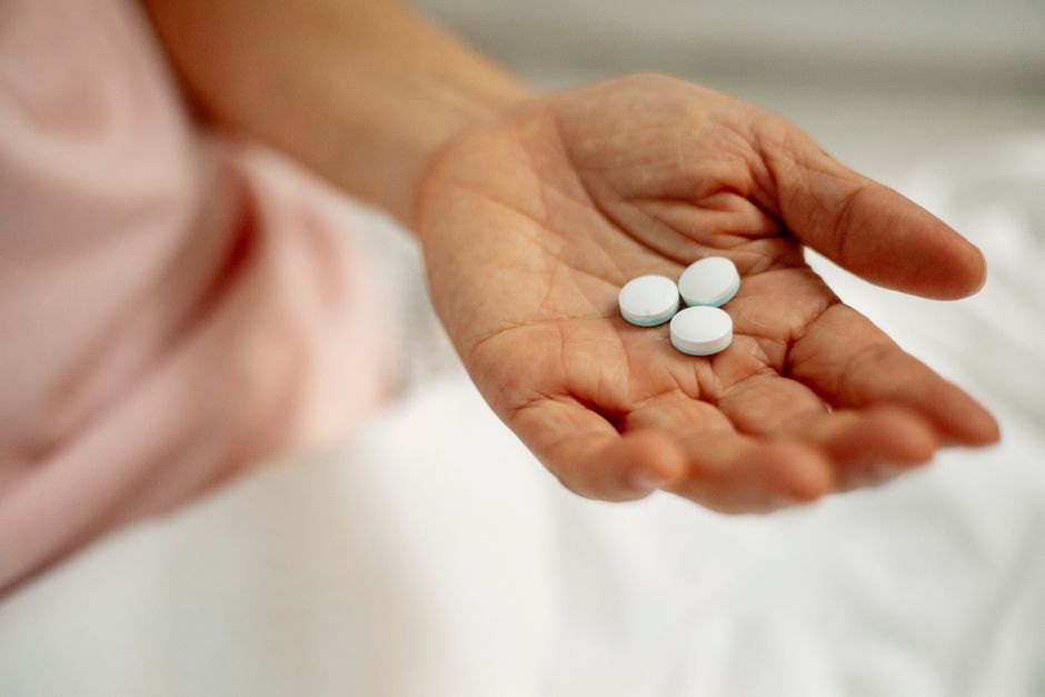 Woman sitting quietly looking emotional while holding a pill bottle of oxycodone
