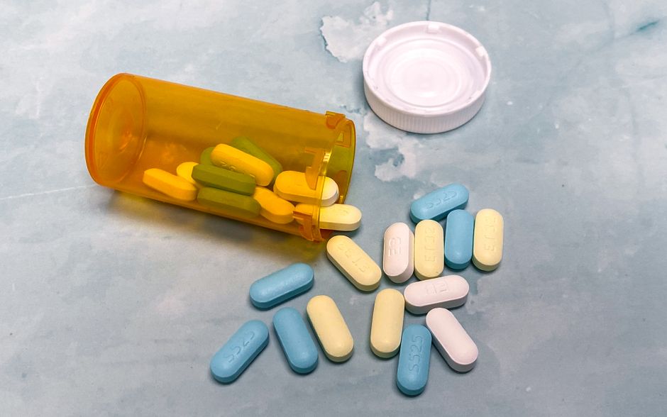 Bottle of hydrocodone pills spilled next to a prescription label representing opioid pain medication