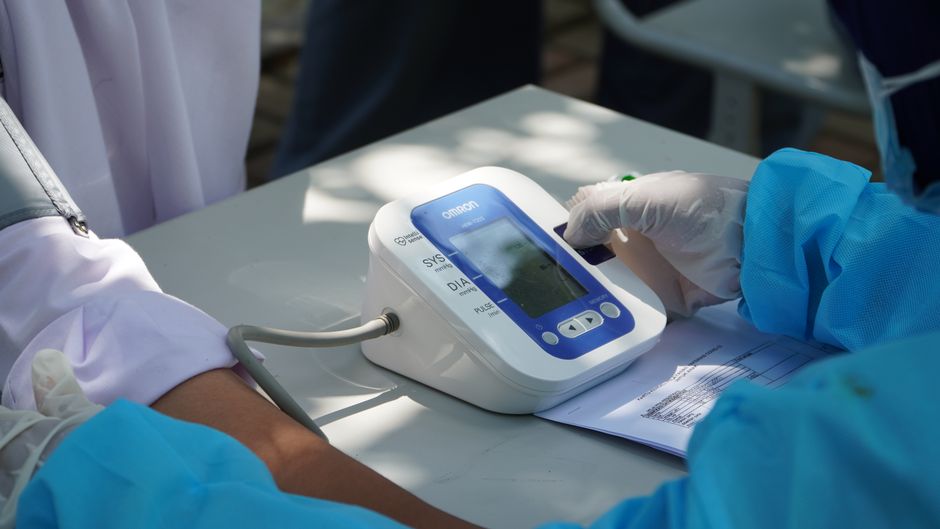 Person checking blood pressure with a monitor next to hydrocodone pills, illustrating the medication's effect on blood pressure