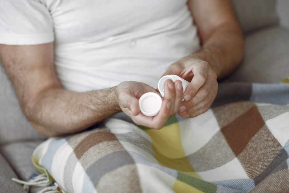 Person looking sleepy while holding a bottle of hydrocodone pain medication
