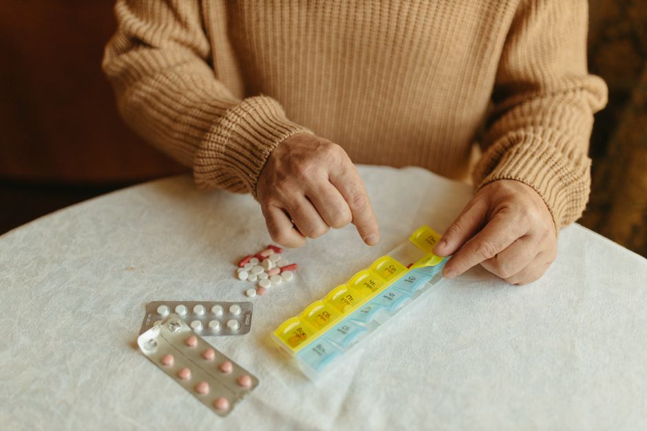 Person organizing oxycodone pills into a labeled weekly pill organizer to prevent medication errors