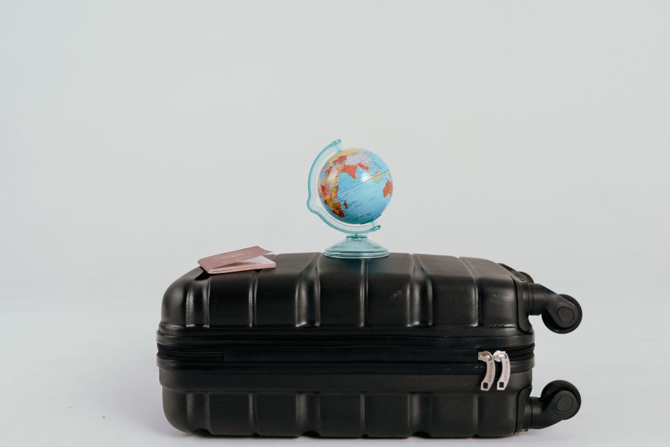 Prescription pill bottle placed next to a passport and suitcase for travel